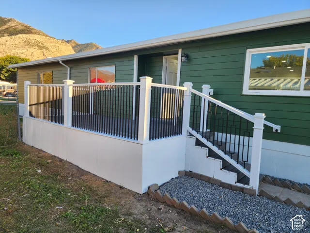 Exterior featuring horizontal siding, white-framed windows, an outdoor deck with white railings and black balusters, and a mountain backdrop