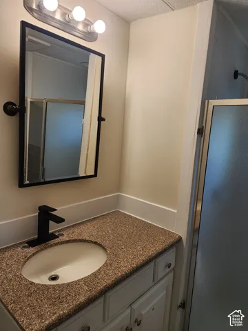 Vanity with speckled countertop, undermount sink, and matte black faucet