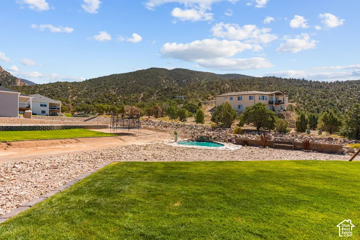 Expansive lawn area with a stone-edged border, a circular in-ground pool, and surrounding rock landscaping