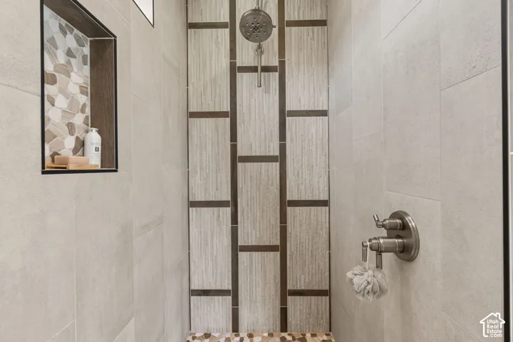 Shower with brushed nickel fixtures, tiled accent wall, and built-in shower niche with mosaic tile
