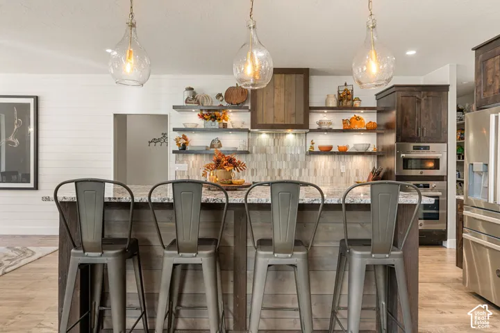 Kitchen island featuring a light-toned countertop, wood-paneled base, and three pendant light fixtures