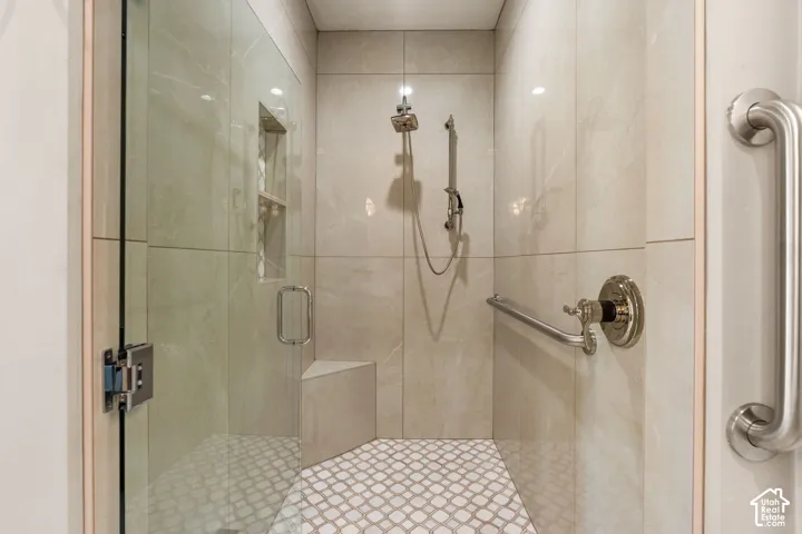 Walk-in shower with full-height tile surround, built-in bench, recessed shelf, and glass enclosure
