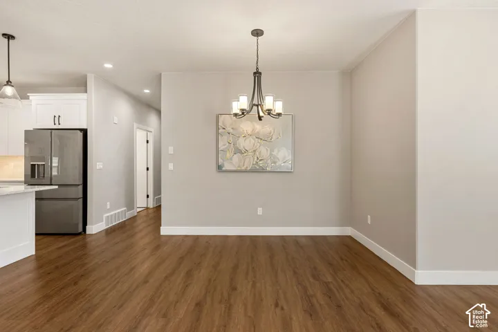 Wood-finish flooring, recessed lighting, and a modern chandelier