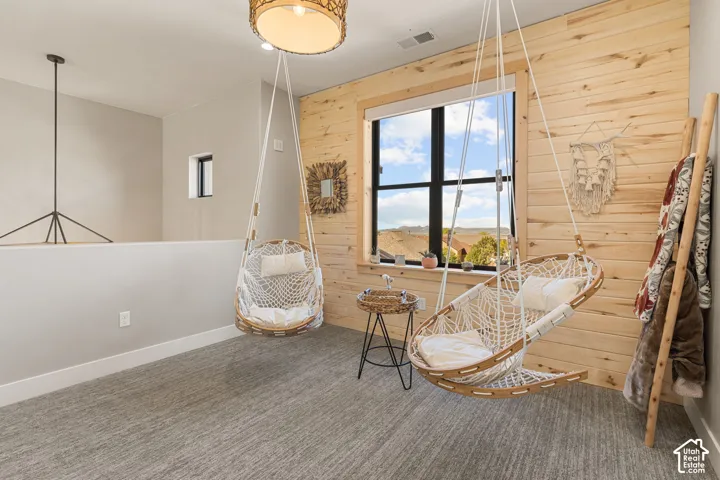 Textured carpeting, wood-paneled accent wall, and a large window providing ample natural illumination