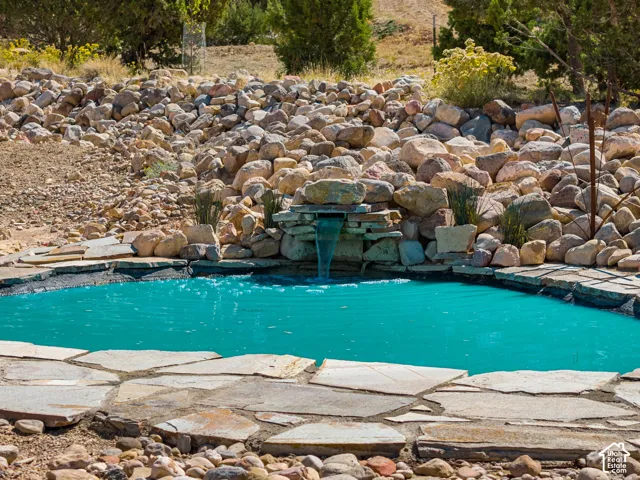Water feature with a stone waterfall, flagstone paving, and surrounding rock landscaping