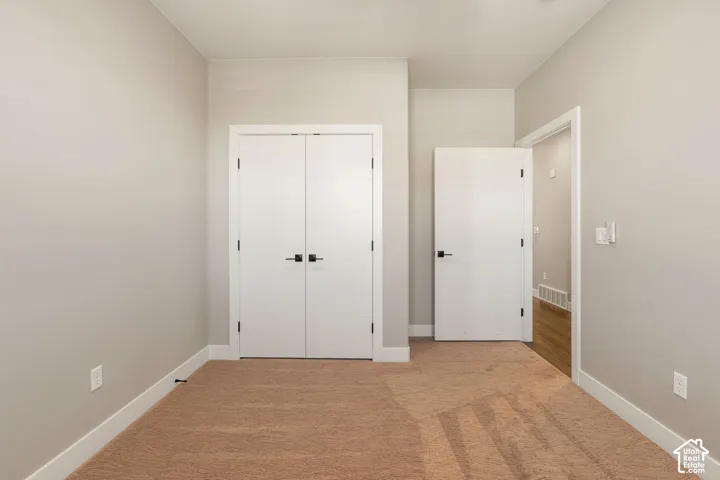 Soft tan carpeting, neutral wall finishes, white trim, and modern white doors with matte black hardware