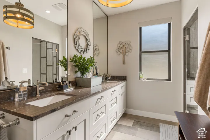 Double vanity with a brown stone countertop, undermount sinks, and white shaker-style cabinetry
