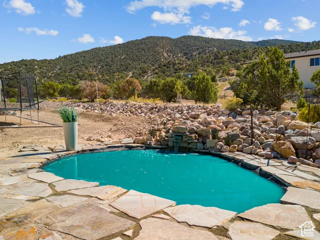 Freeform inground pool with a stone waterfall feature, surrounded by flagstone paving and natural rock landscaping