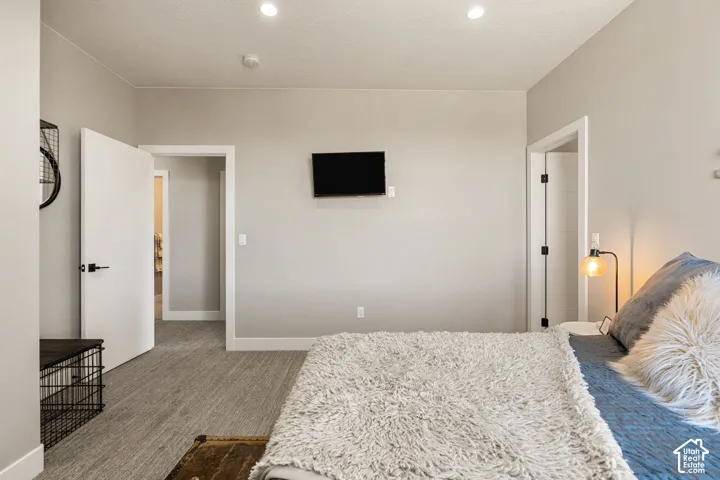 Recessed ceiling lighting illuminates the room with light gray walls and light-toned patterned carpet