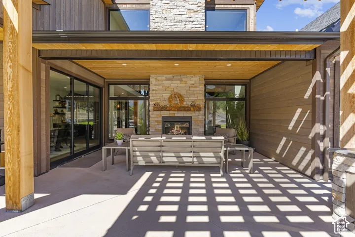 Covered patio with a stone-clad fireplace and wood plank ceiling