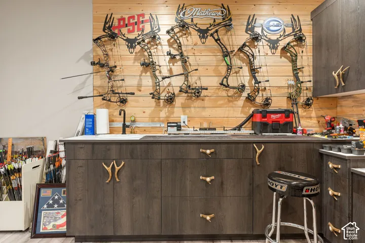 Custom cabinetry with antler-shaped hardware, integrated sink, matte black faucet, and wood-finish flooring