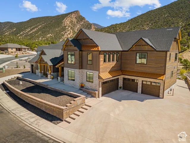 Multi-level residence featuring a multi-car garage, stone and wood-paneled exterior, and copper-toned accents