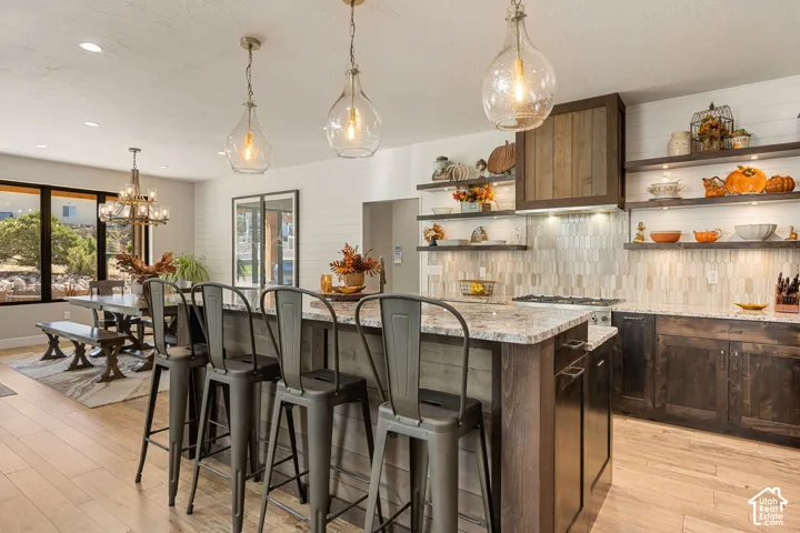 Kitchen island with a light-toned countertop, wood-finish flooring, and recessed and pendant lighting