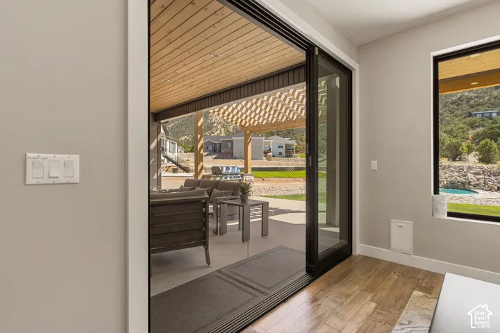 Sliding glass door opening to a covered patio with a wood-finish ceiling and pergola
