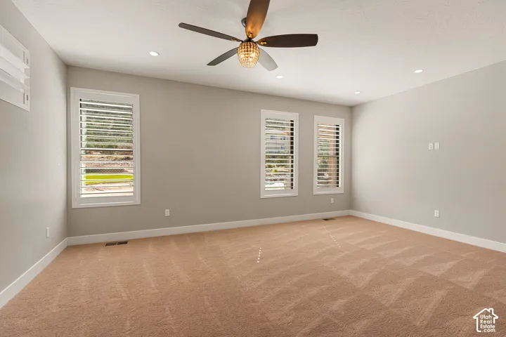 Spacious room featuring neutral paint, recessed lighting, and a ceiling fan with integrated light