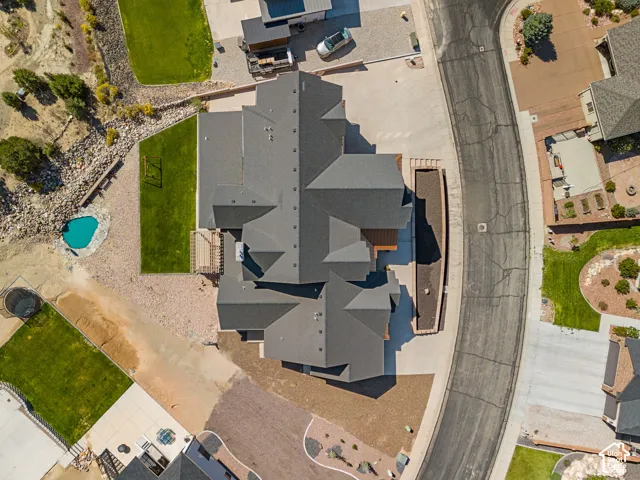 Multiple-pitch roofline, gravel landscaping, manicured lawn areas, curved driveway, and a distinct turquoise-colored pool