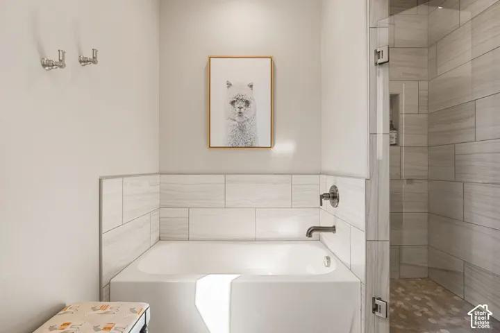 Built-in bathtub with subway tile surround, dark bronze fixtures, and a frameless glass shower enclosure featuring coordinating tile
