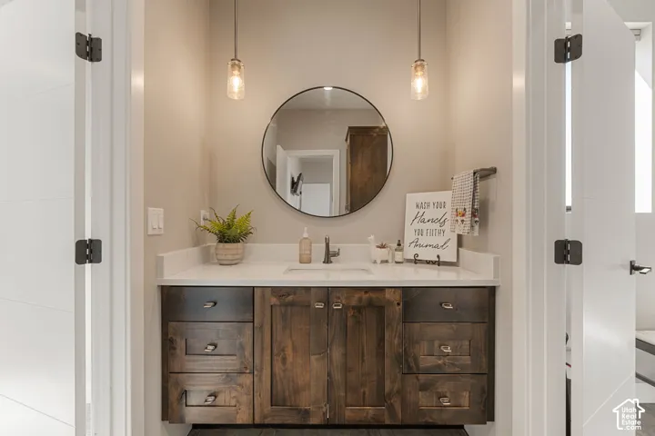 Floating wood-finish vanity with a light-toned countertop, under-mount sink, and dual pendant lighting