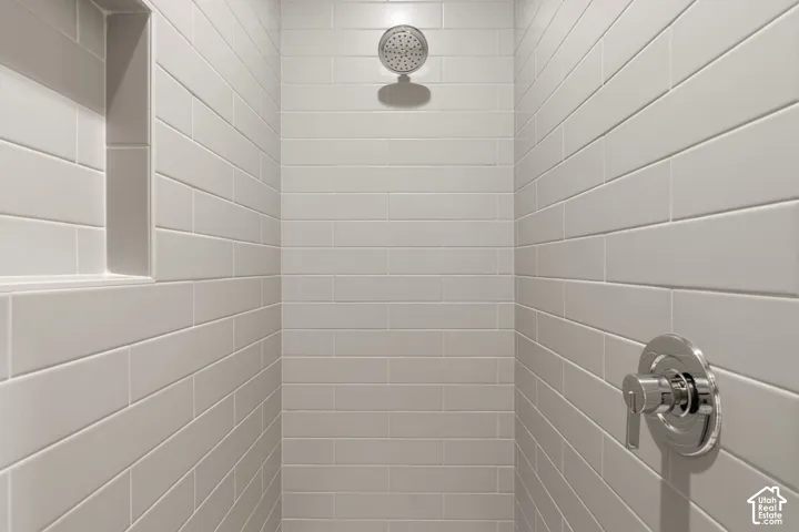 Tiled shower featuring a rainfall showerhead, polished chrome fixtures, and a recessed niche