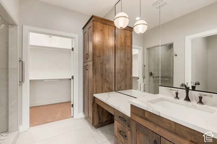 Dual vanity with white countertop and integrated sinks, wood-finish cabinetry, and globe pendant lighting