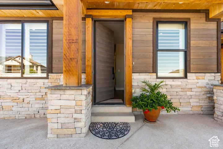 Stacked stone and wood-paneled exterior with a prominent wood beam column and a solid wood entry door