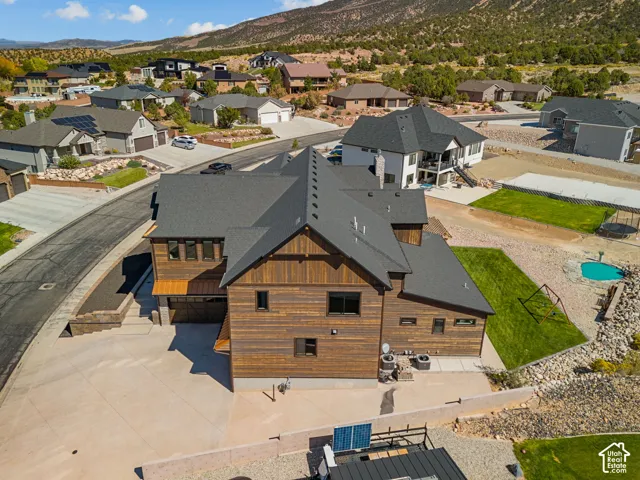 Expansive exterior featuring wood-finish siding, a dark shingle roof, a generously sized driveway, and a backyard with a pool