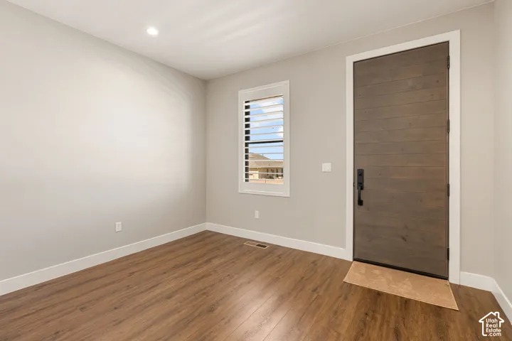 Wood-finish flooring, white trim, recessed lighting, and a window with plantation shutters