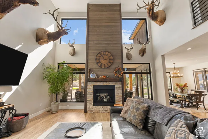 Two-story great room with a stone fireplace, wood-finish flooring, and large windows