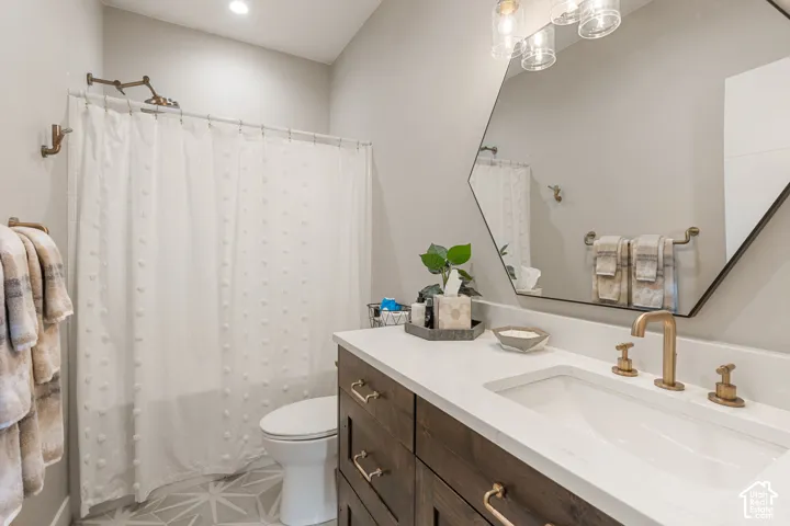 Bathroom featuring a wood-finish vanity with an integrated sink, a white countertop, and brass-tone fixtures