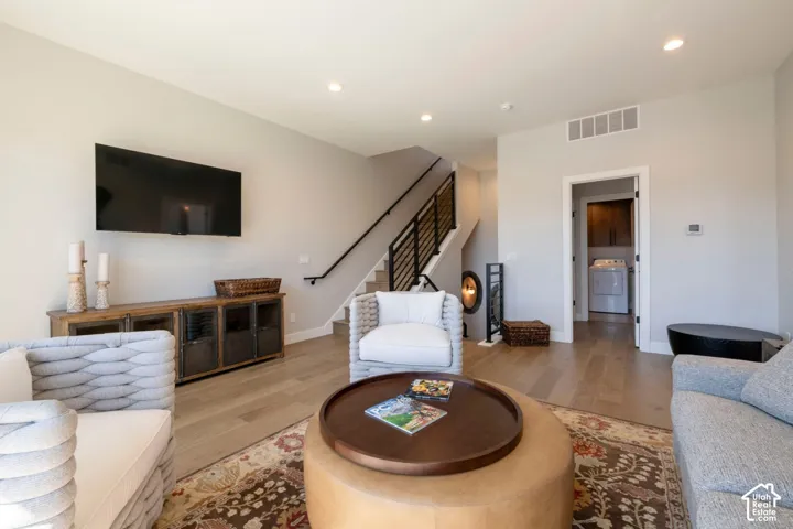 Recessed lighting, wood-finish flooring, and contemporary staircase with metal balusters