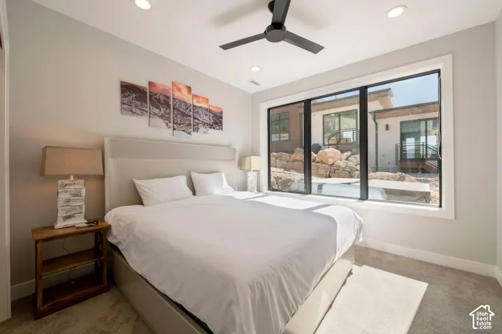 Recessed lighting, ceiling fan, expansive window, neutral wall tones, and plush carpet flooring