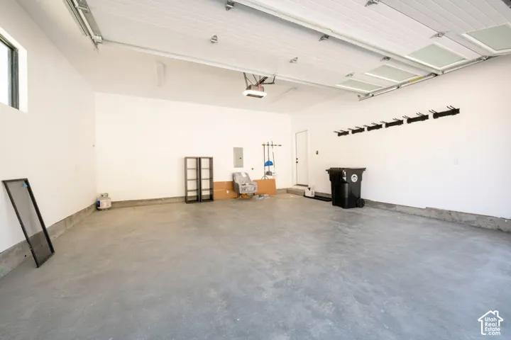 Spacious garage with light gray concrete flooring, white walls, and an overhead garage door featuring translucent panels