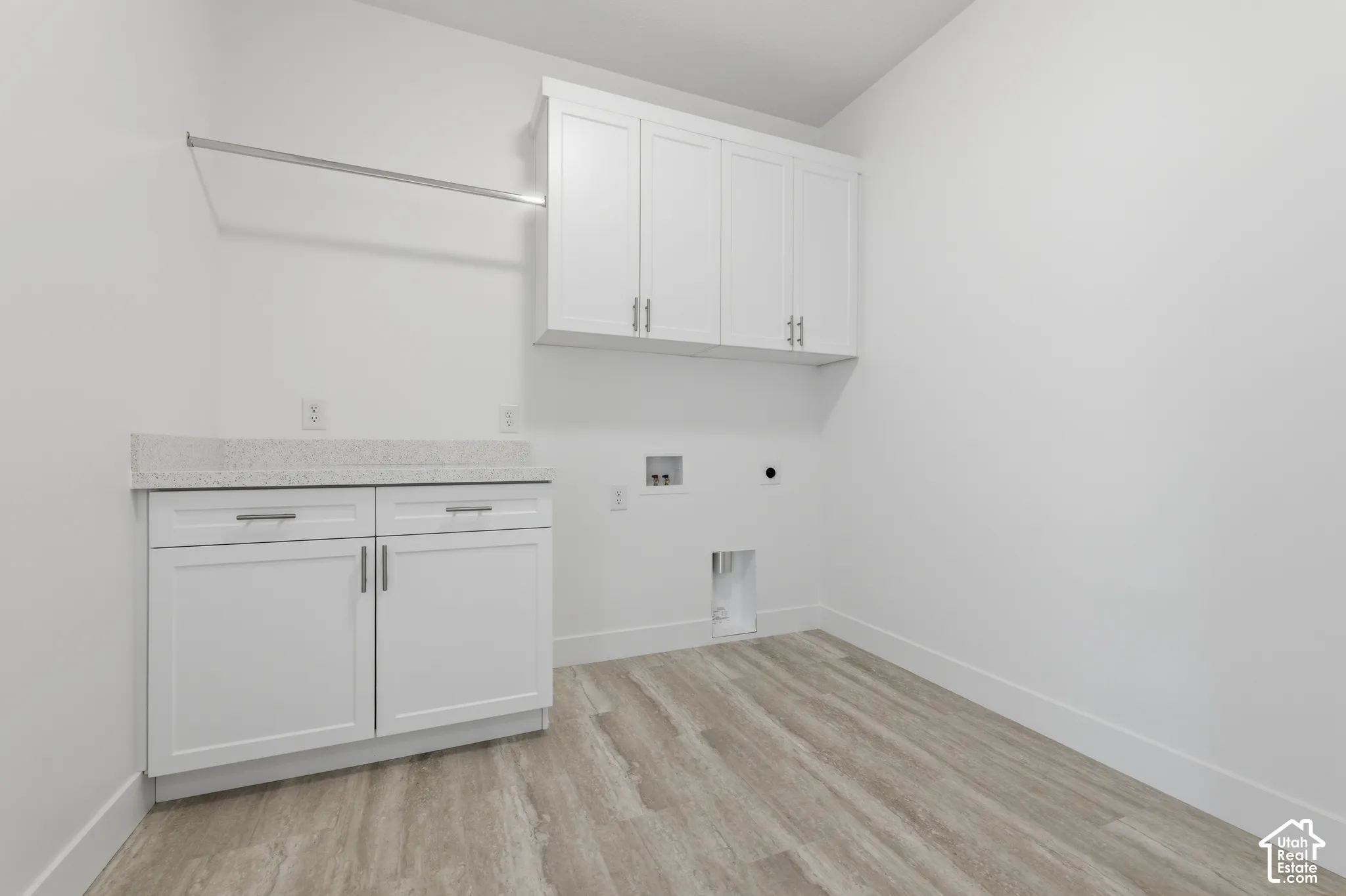 White cabinetry with silver-tone pulls, light-toned countertop, and wood-finish flooring