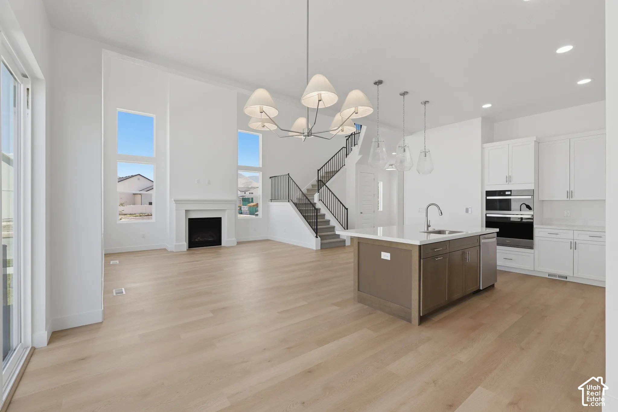 Open-concept living space with wood-finish flooring, a contemporary fireplace, and high ceilings