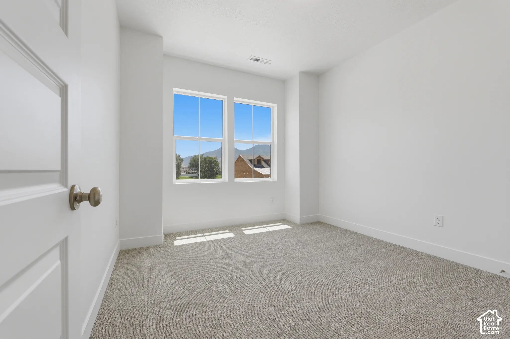 Bright room with two double-hung windows, light gray carpet, and white walls