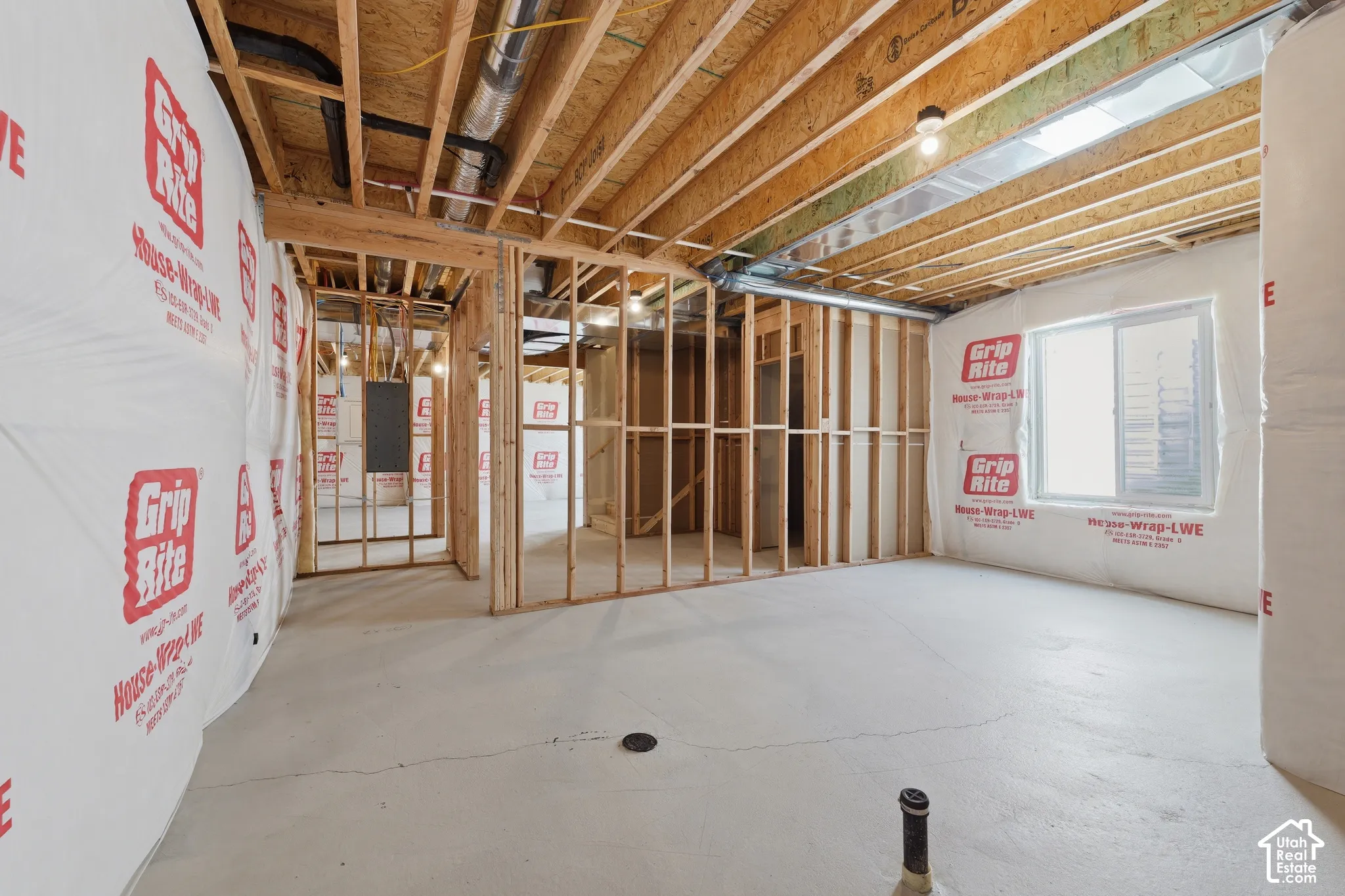 Unfinished basement with exposed wood framing, concrete flooring, and a single-pane window