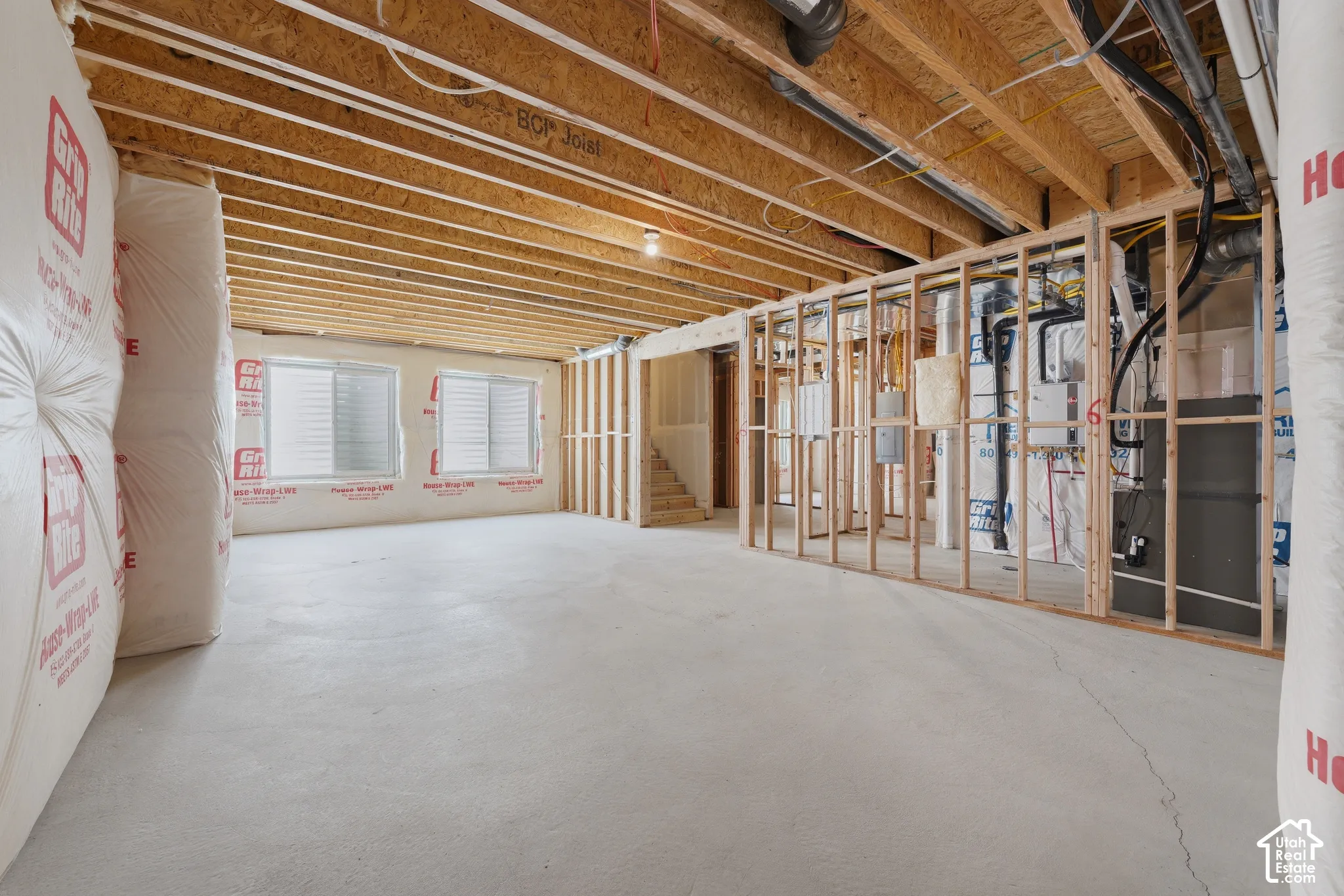 Unfinished lower level with wood framing, exposed joists, concrete flooring, and multiple windows