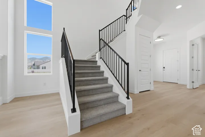 Light wood-finish flooring with a carpeted staircase and black metal railings