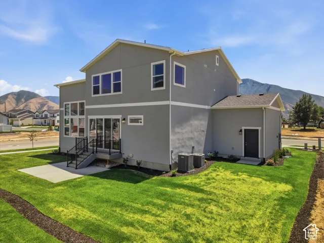 Expansive backyard with a manicured lawn, concrete patio, and mature landscaping