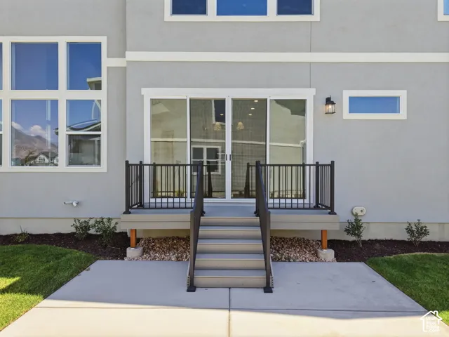 Concrete patio with a composite deck, black metal railings, and dual sliding glass doors