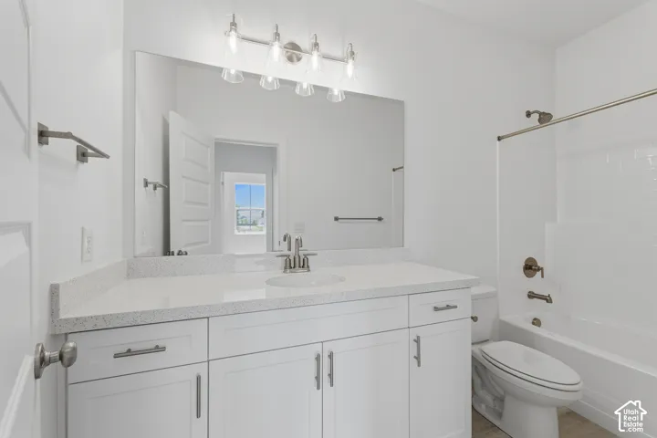 White vanity with brushed nickel hardware, quartz-finish countertop, single basin sink, brushed nickel faucet, and a wall-mounted light fixture
