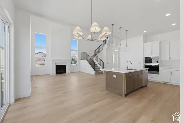 Open-concept living space with wood-finish flooring, a contemporary fireplace, and high ceilings