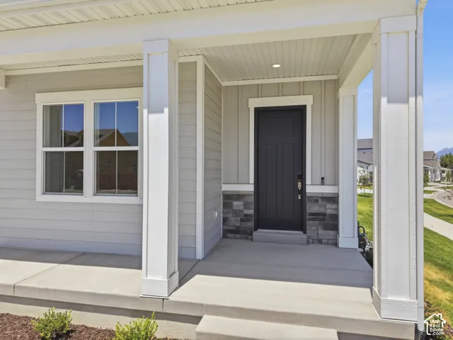 Covered front porch with white columns, light gray horizontal siding, and stone-look accent paneling
