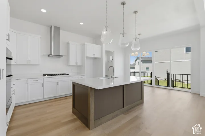 Gourmet kitchen with white cabinetry, stainless steel appliances, and a central island with a sink