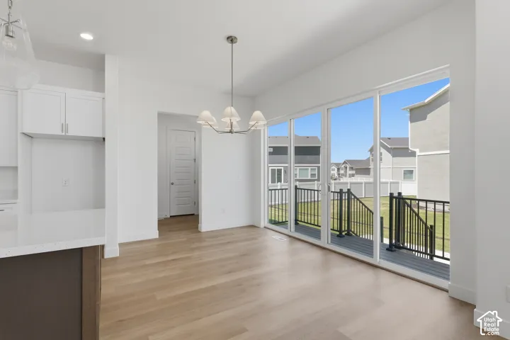 Wood-finish flooring, white cabinetry, quartz countertop, large sliding glass doors, and a deck with dark railings