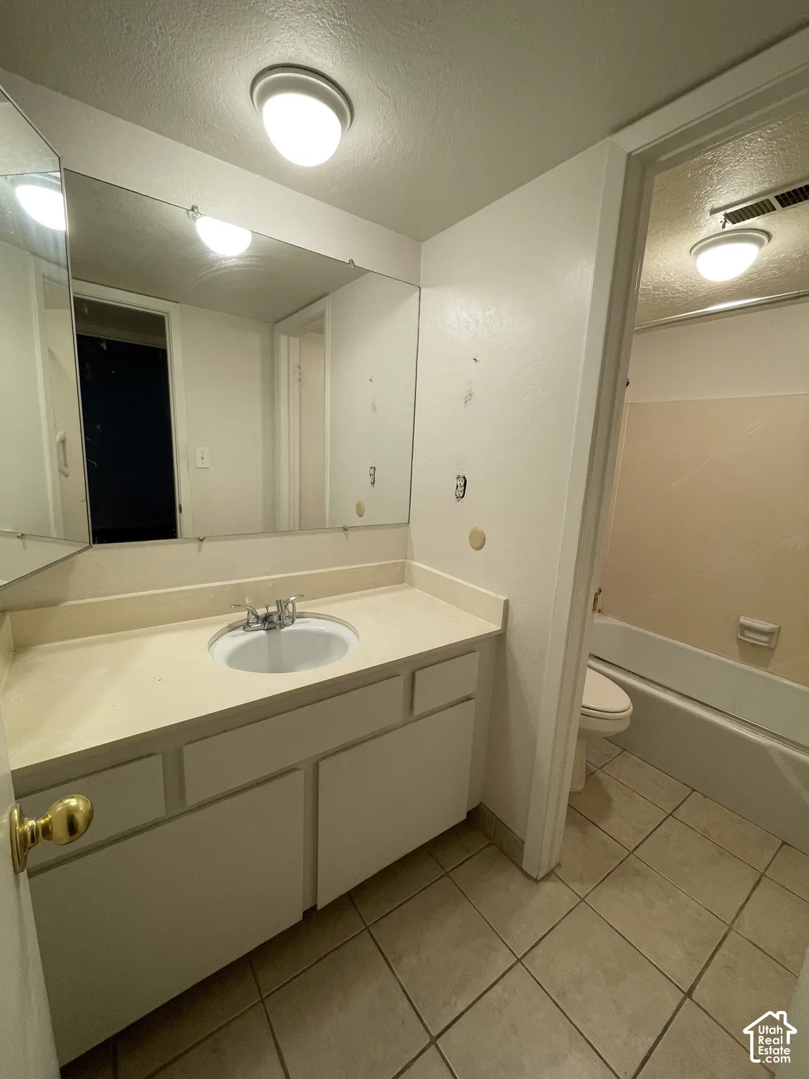 Bathroom featuring a vanity with an integrated sink, a large wall-mounted mirror, and tile flooring