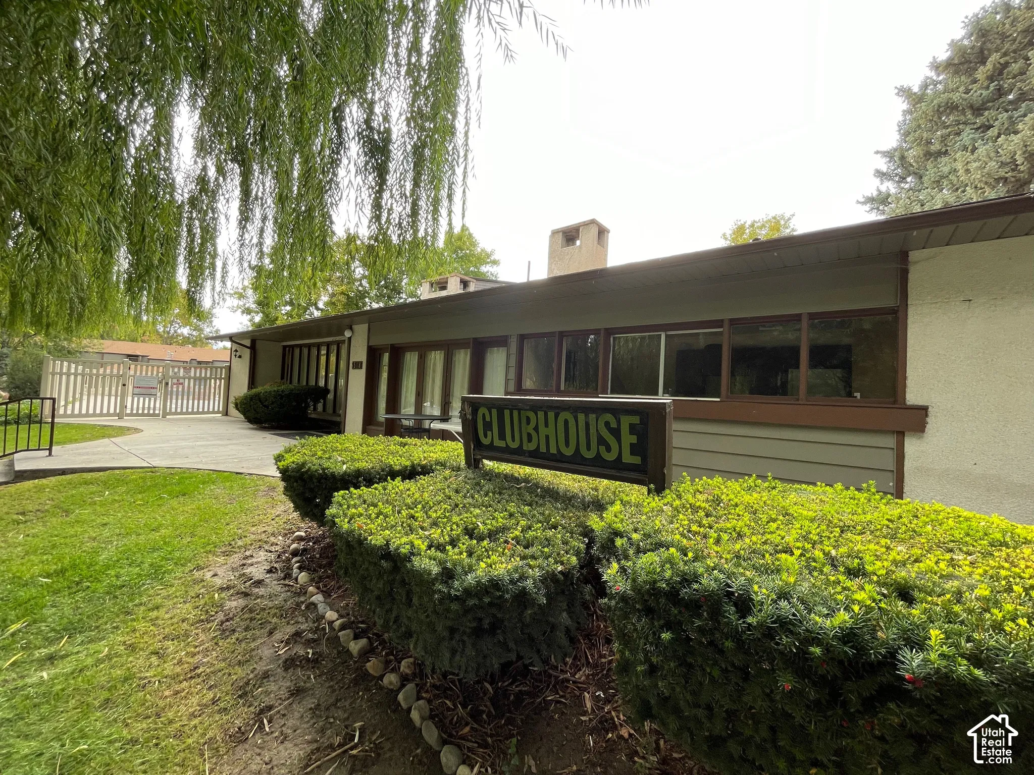 Clubhouse building with wood-finish siding, multiple windows, and a paved walkway