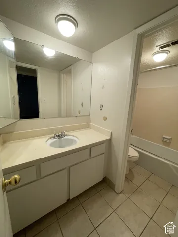 Bathroom featuring a vanity with an integrated sink, a large wall-mounted mirror, and tile flooring