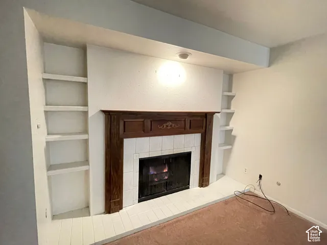 Fireplace with wood mantel and tile surround, flanked by built-in shelving on both sides