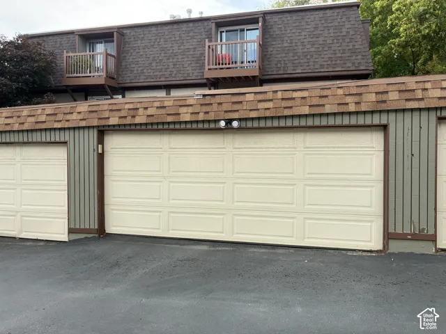 Multiple garage doors with paneling, upper-level balconies with wood railings, and a shingled roofline